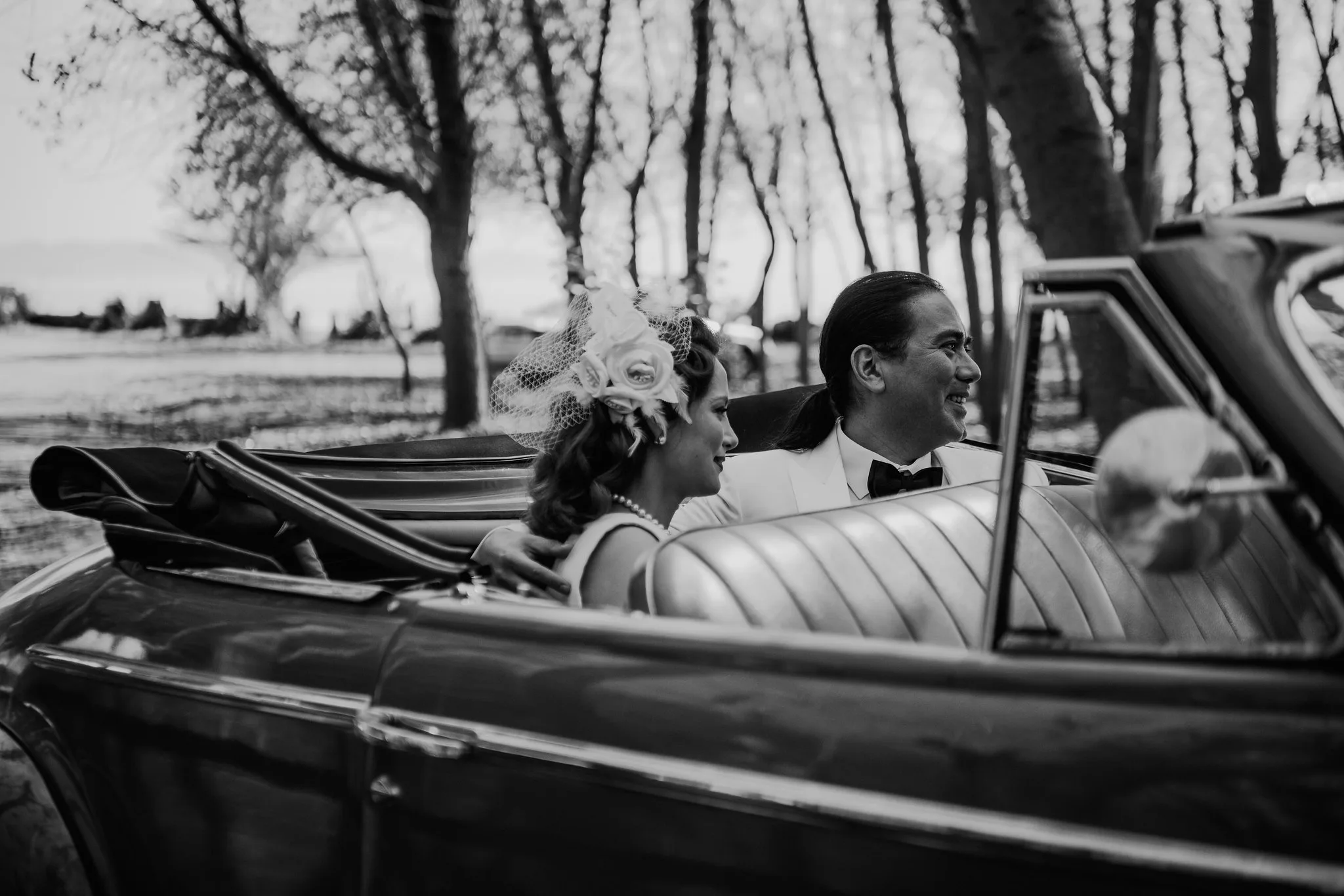 Novios sonriendo en el asiento del auto clásico, blanco y negro
